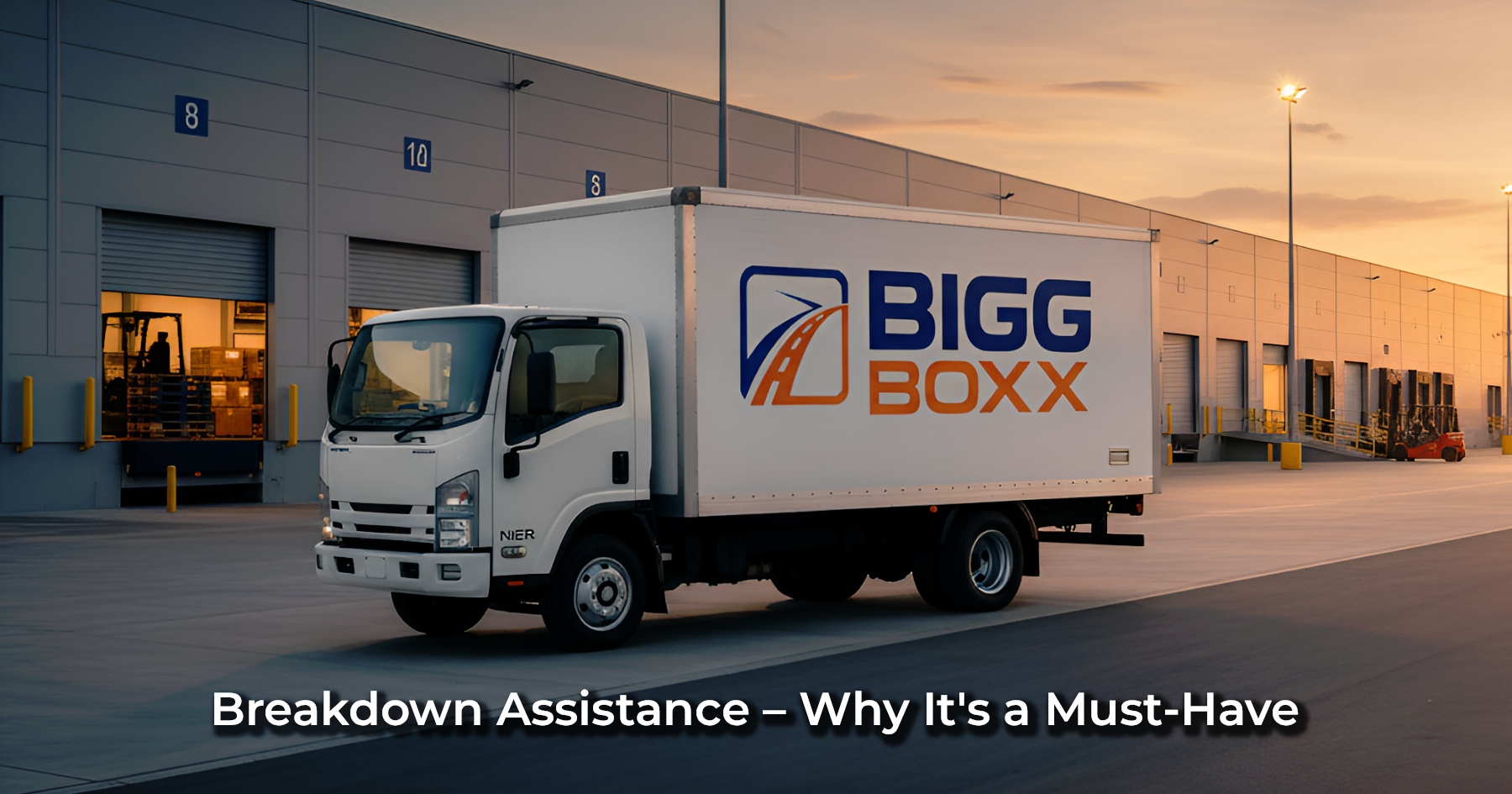 Side profile of a white Bigg Boxx rental box truck parked at a large warehouse loading dock during sunset | Breakdown Assistance – Why It's a Must-Have | Bigg Boxx Rentals