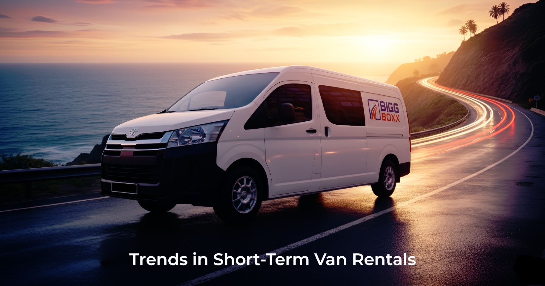A white Bigg Boxx rental van driving along a winding coastal road at sunset, with ocean waves on one side and a steep cliff on the other | Trends in Short-Term Van Rentals | Bigg Boxx Rentals